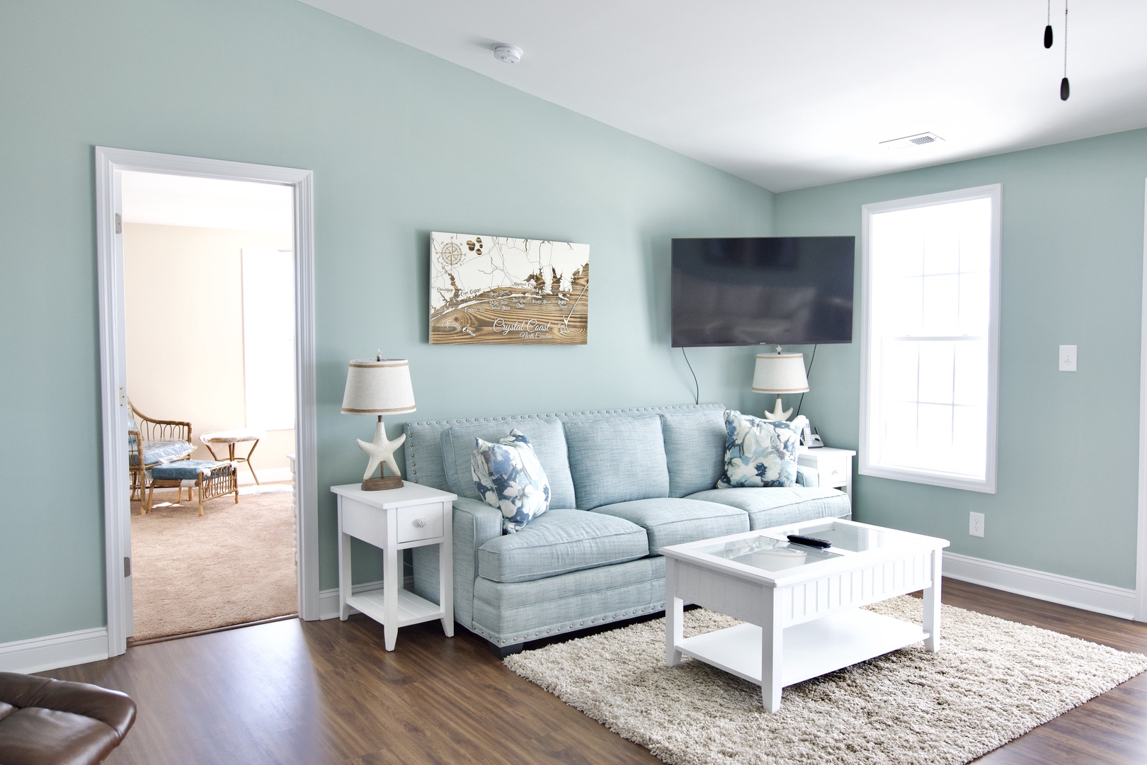 Sink into this serene living room's plush sofa and unwind with your favorite shows on the flat-screen TV in calming coastal hues.