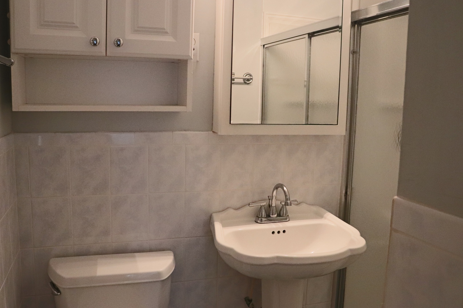 Your private bathroom features a classic pedestal sink with gleaming fixtures and a convenient glass shower enclosure for refreshing moments.