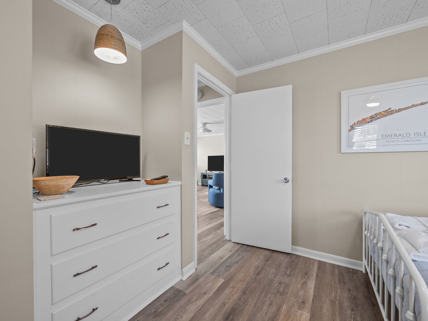 Your cozy bedroom features clean modern furnishings, a flat-screen TV, and coastal artwork that sets a peaceful tone for your getaway.