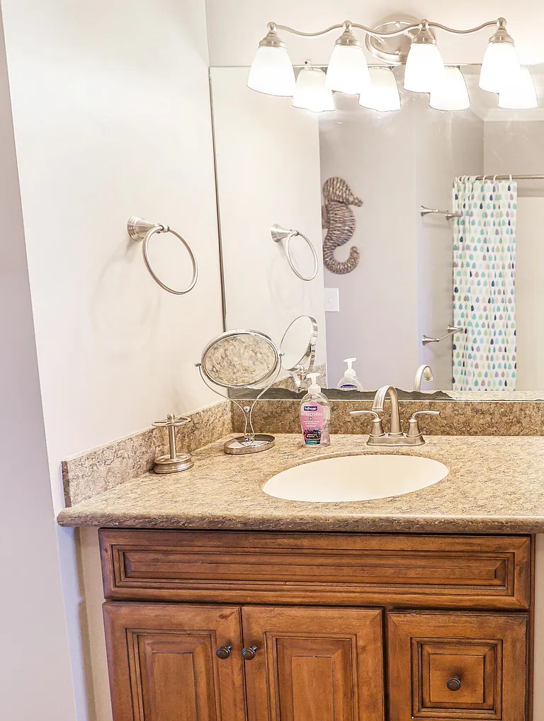 Refresh in your elegant bathroom with granite countertops, warm wood cabinetry, and thoughtful coastal touches that make getting ready a pleasure.