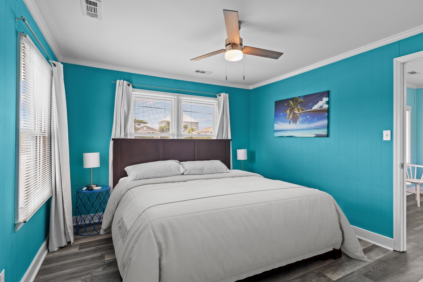 Drift off to sleep in this vibrant coastal bedroom, where soft linens and calming turquoise walls create your perfect beach getaway retreat.