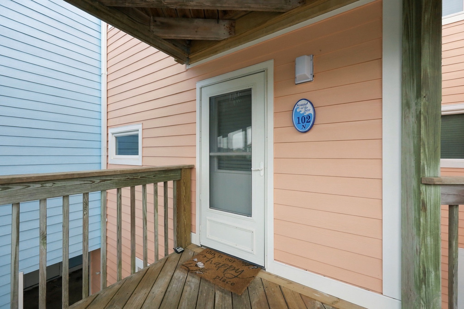 The cheerful coral exterior and welcoming covered entry mark your arrival at this charming coastal retreat, where relaxation begins the moment you step through the door.