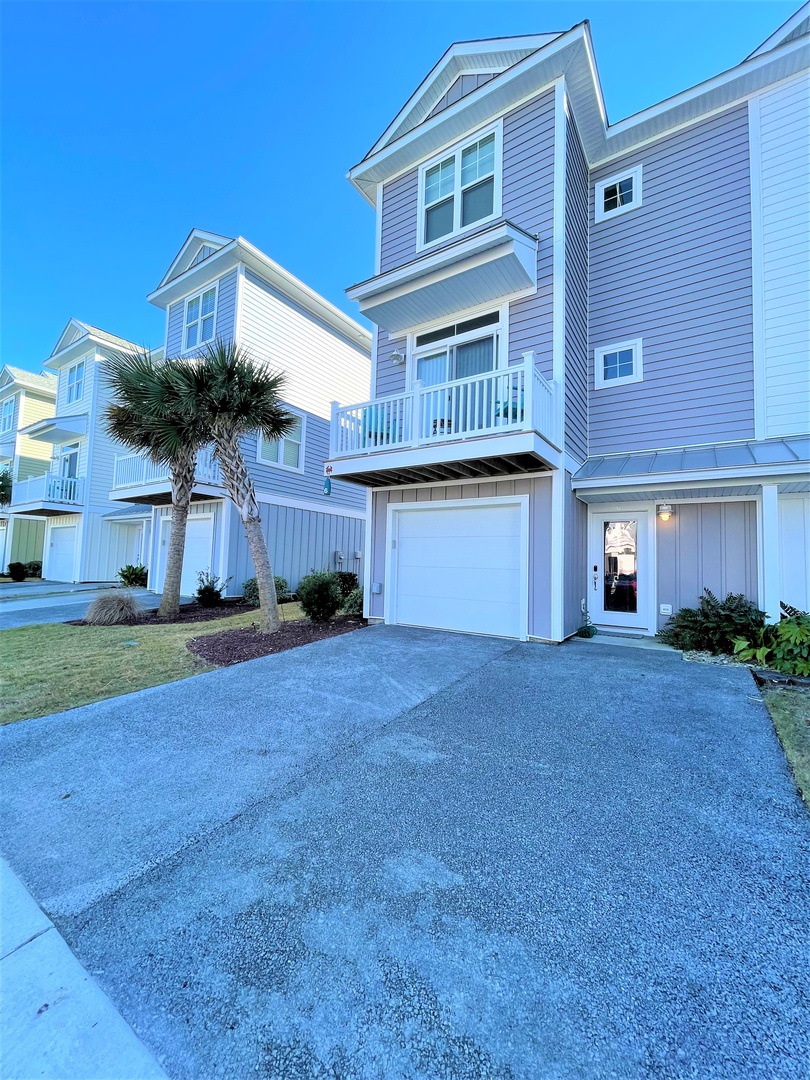 Modern coastal townhome with private garage and tropical landscaping in a pristine beachside community.