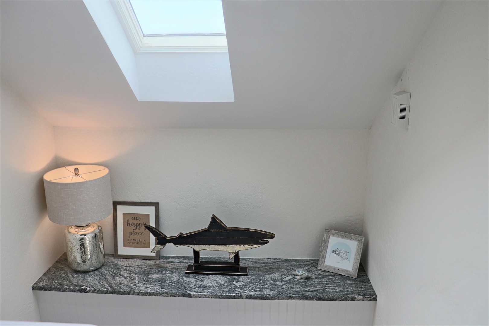 Your cozy loft nook features a charming display with natural light from the skylight above, creating a peaceful reading corner.