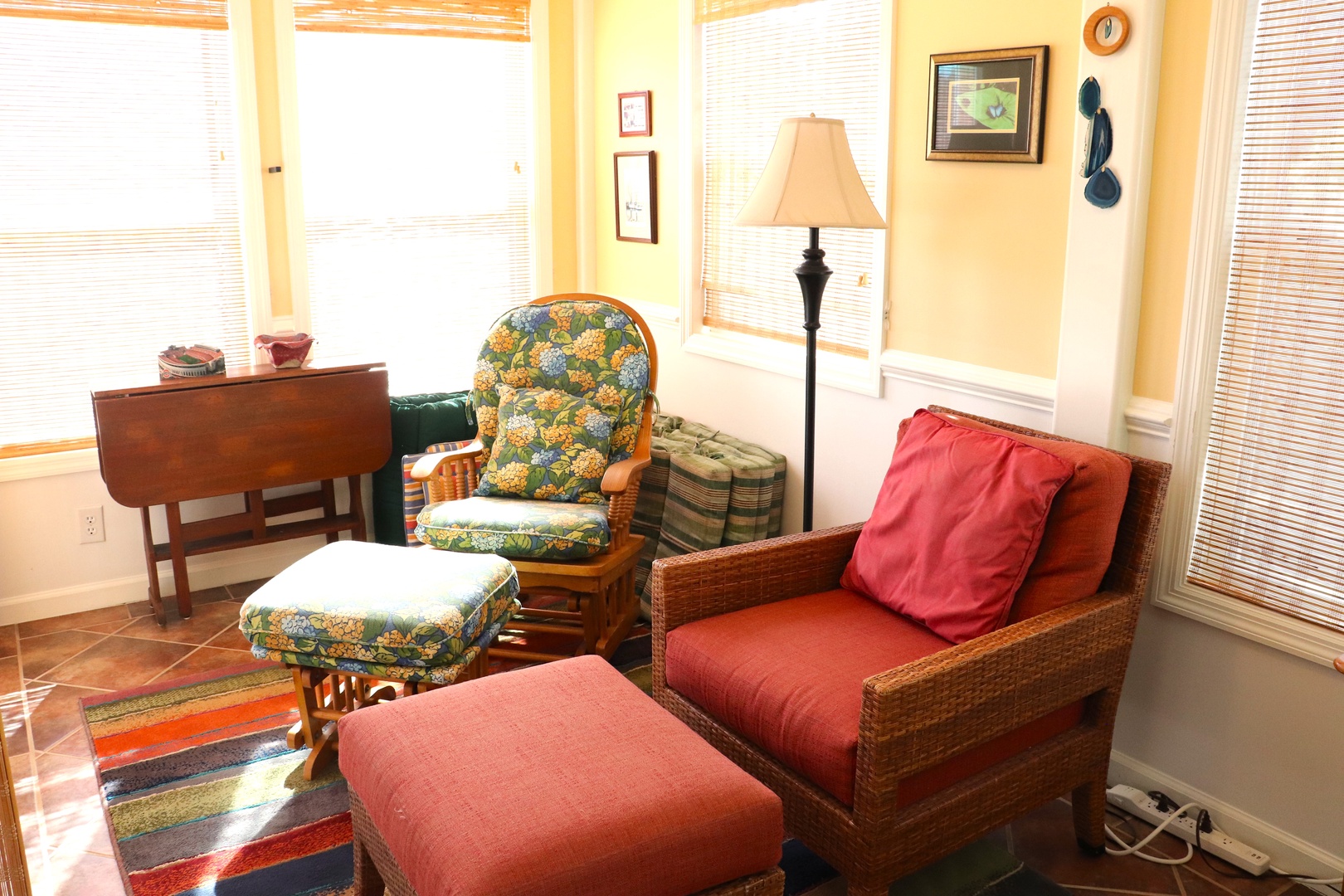 Sink into comfortable wicker seating with colorful cushions, where natural light floods through bamboo blinds in your cozy living space.