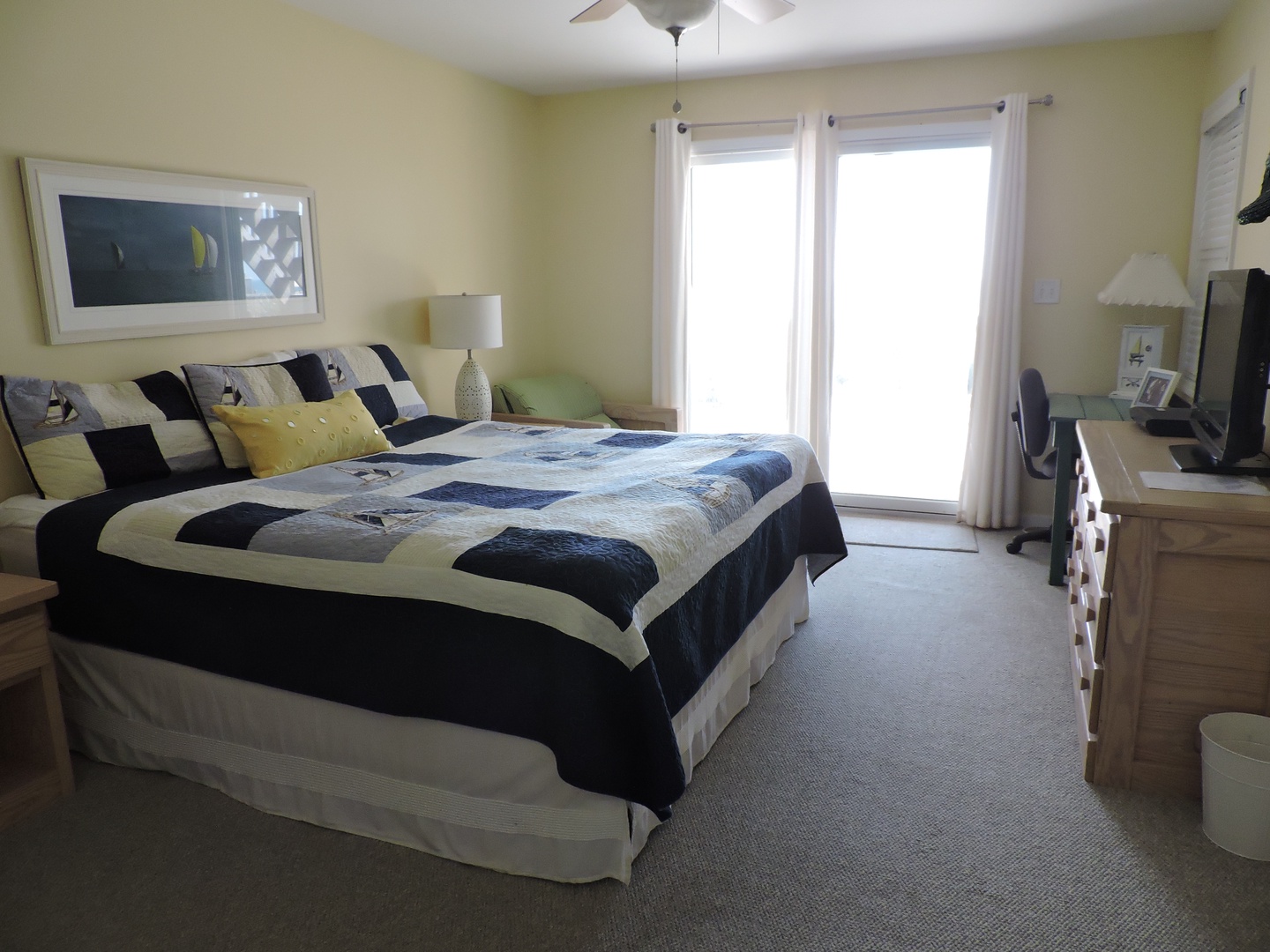 Wake up in your bright, comfortable bedroom featuring crisp nautical linens and morning light streaming through sliding doors to your private balcony.