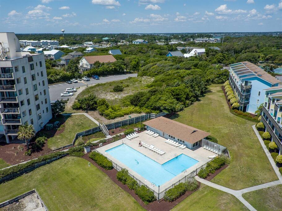 Aerial view showcasing the resort complex with swimming pool, buildings, and surrounding coastal landscape with lush vegetation.