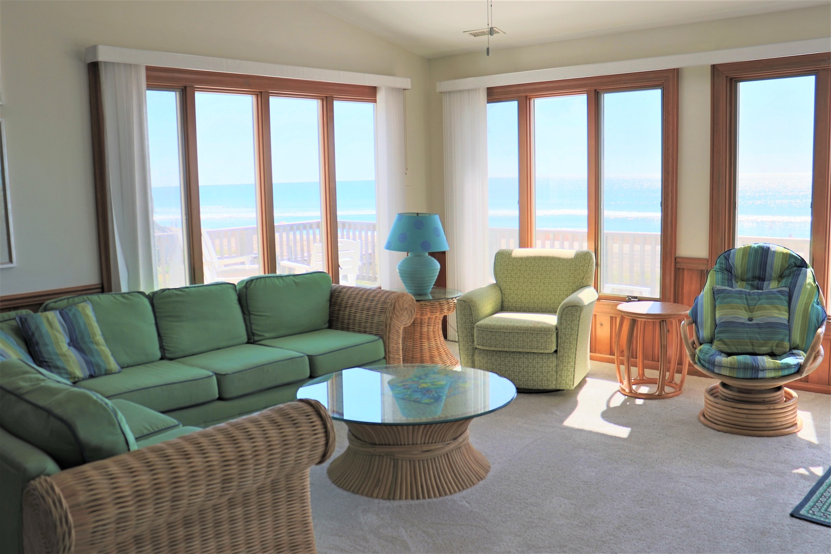 Relax in this bright living room with ocean views. Sink into the plush green sofa and enjoy the sea breeze through floor-to-ceiling windows.