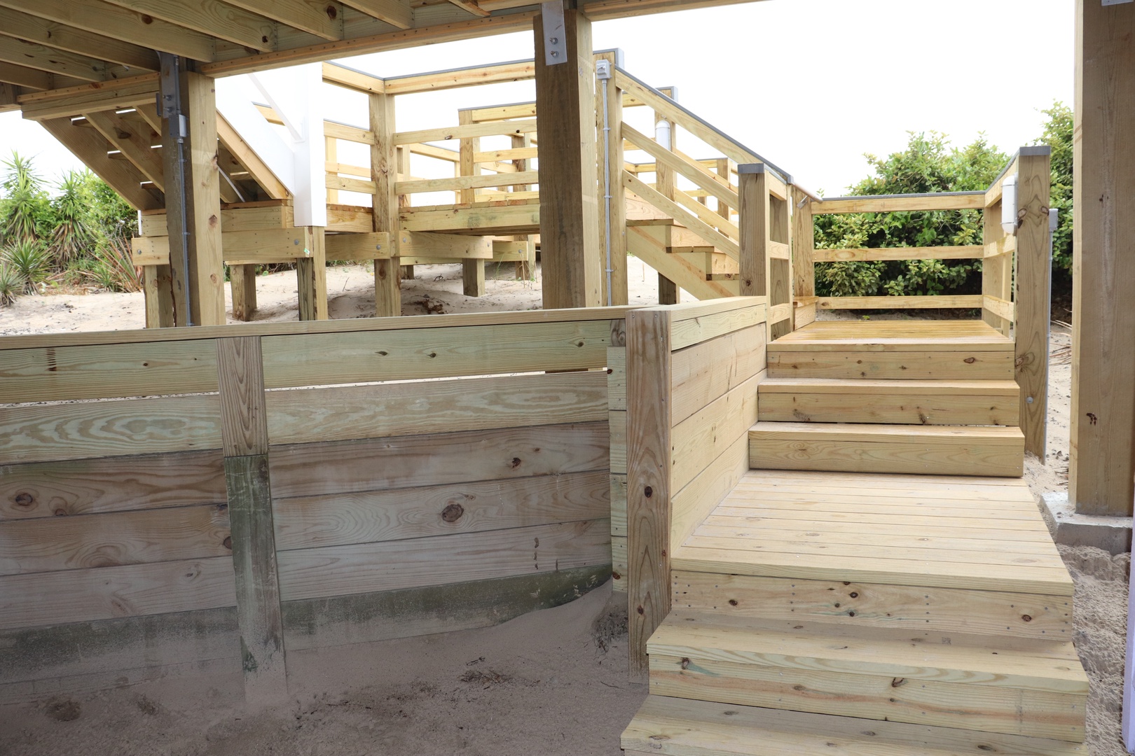Fresh timber boardwalk and steps connect different levels of the beachfront property, creating easy access through natural dune landscape.