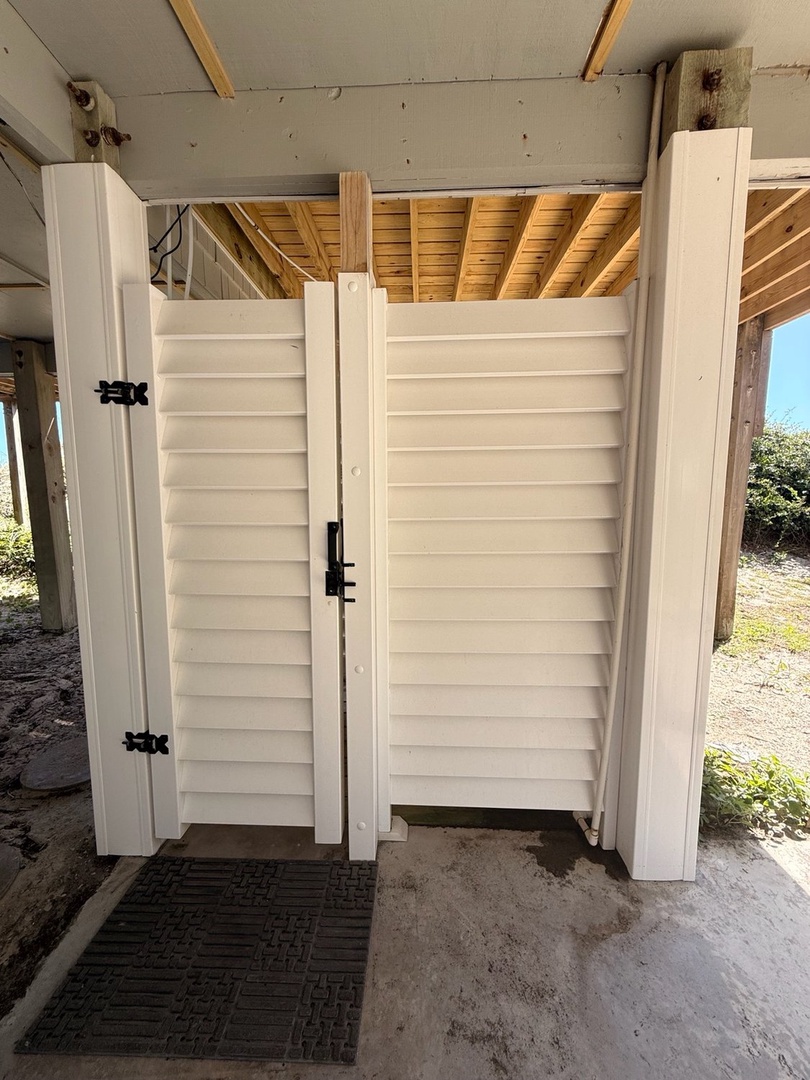 Rinse off the salt and sand in your private outdoor shower beneath the house, a breezy coastal convenience after a perfect beach day.