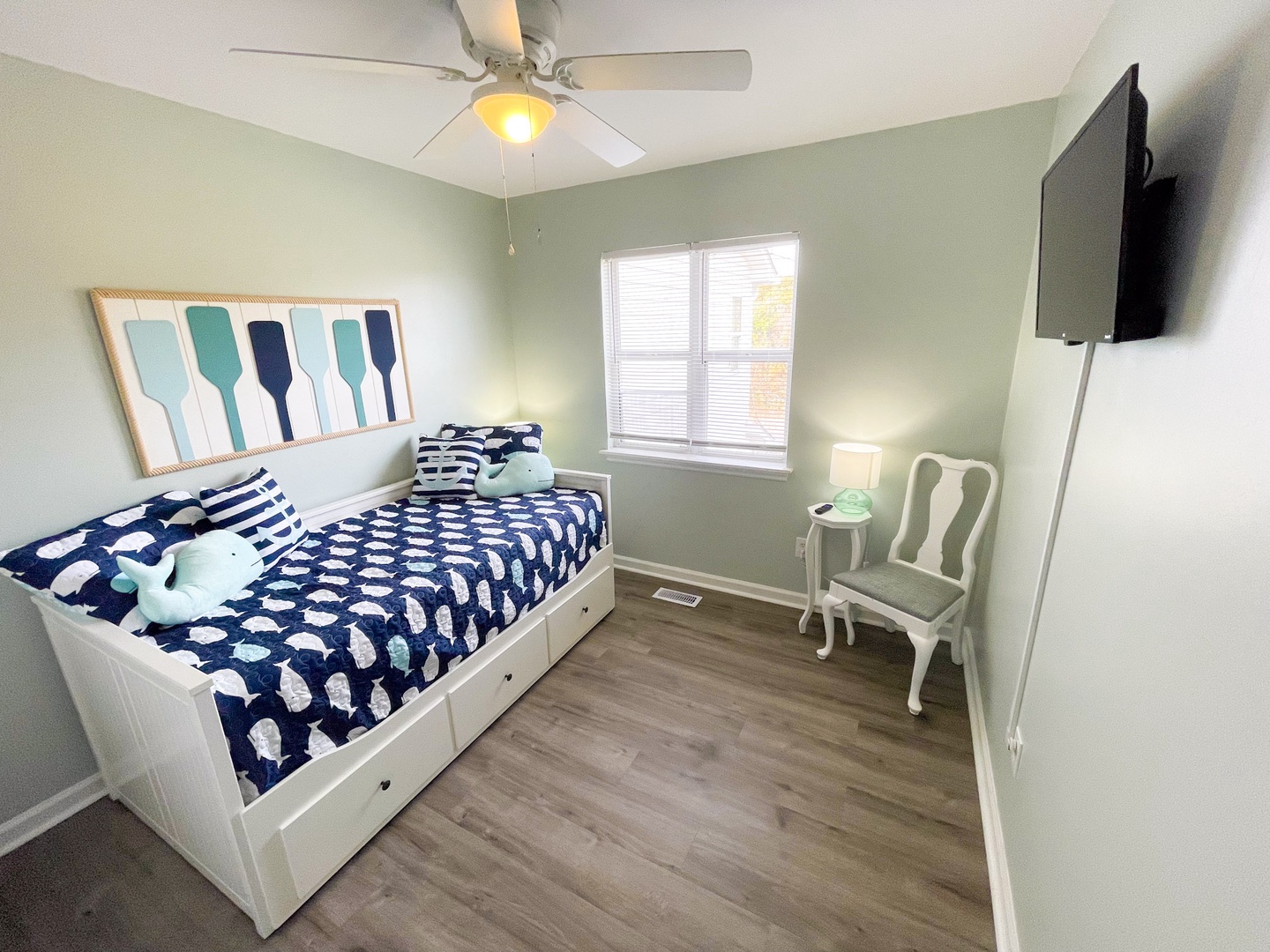 Unwind in your cozy bedroom with nautical charm, featuring a comfortable daybed and wall-mounted TV for relaxing evenings.