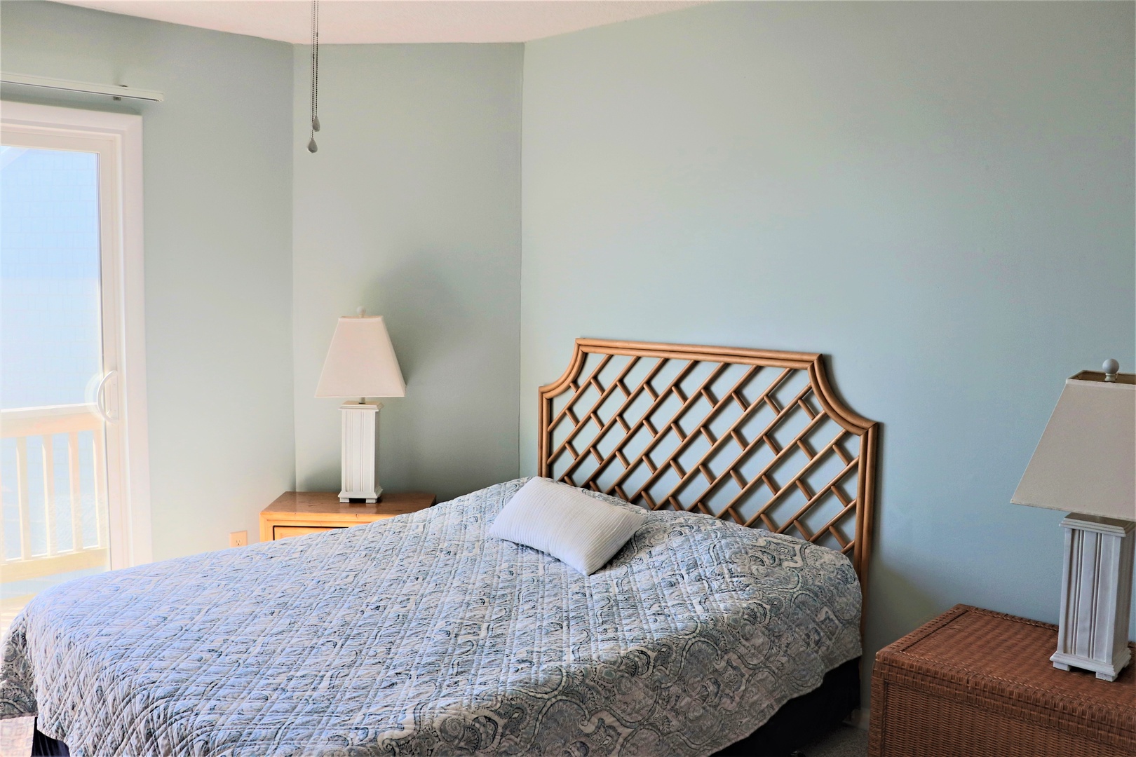 Sink into comfort in your serene bedroom with its elegant bamboo headboard and soft blue walls creating the perfect peaceful retreat.