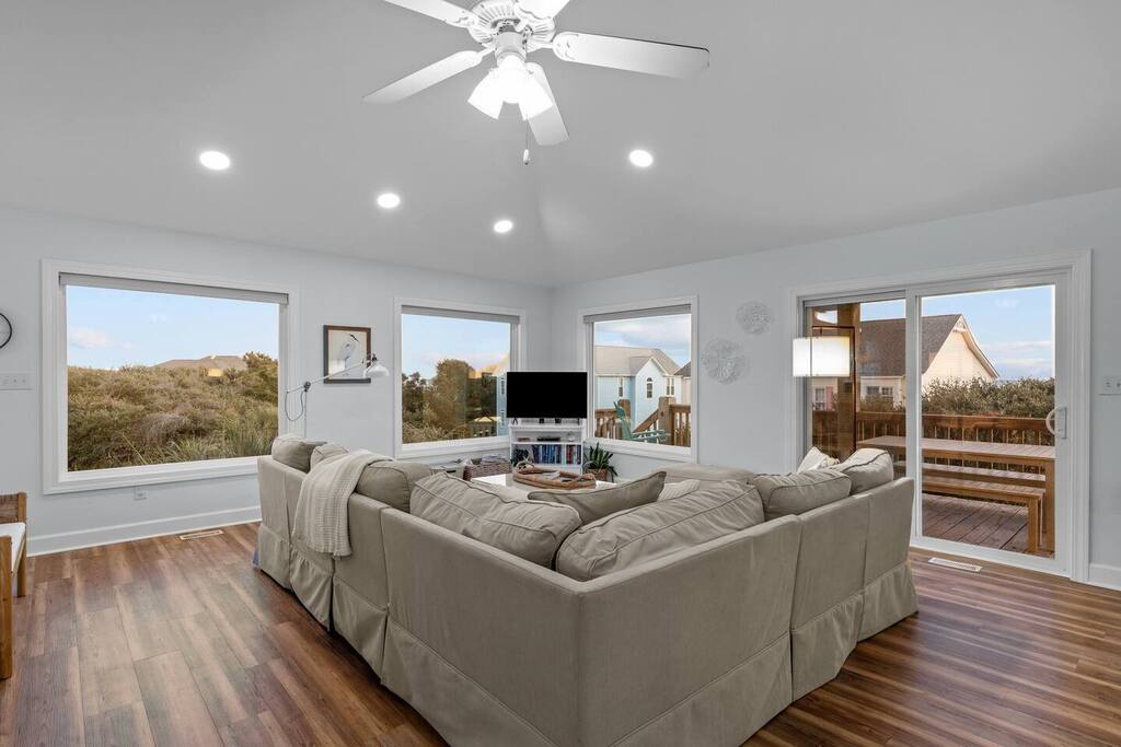 Unwind in your spacious living room with plush sectional seating, warm hardwood floors, and bright windows showcasing scenic views.