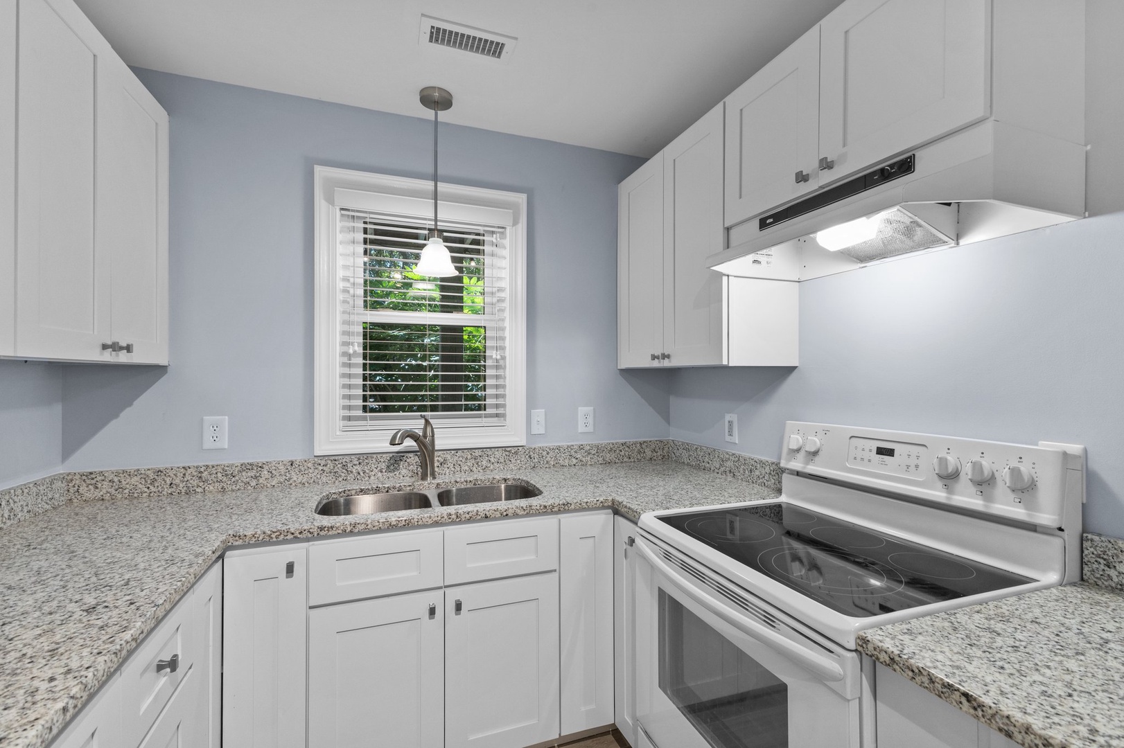 Your bright, efficient kitchen features granite countertops, white appliances, and plenty of cabinet space for preparing delicious meals during your stay.
