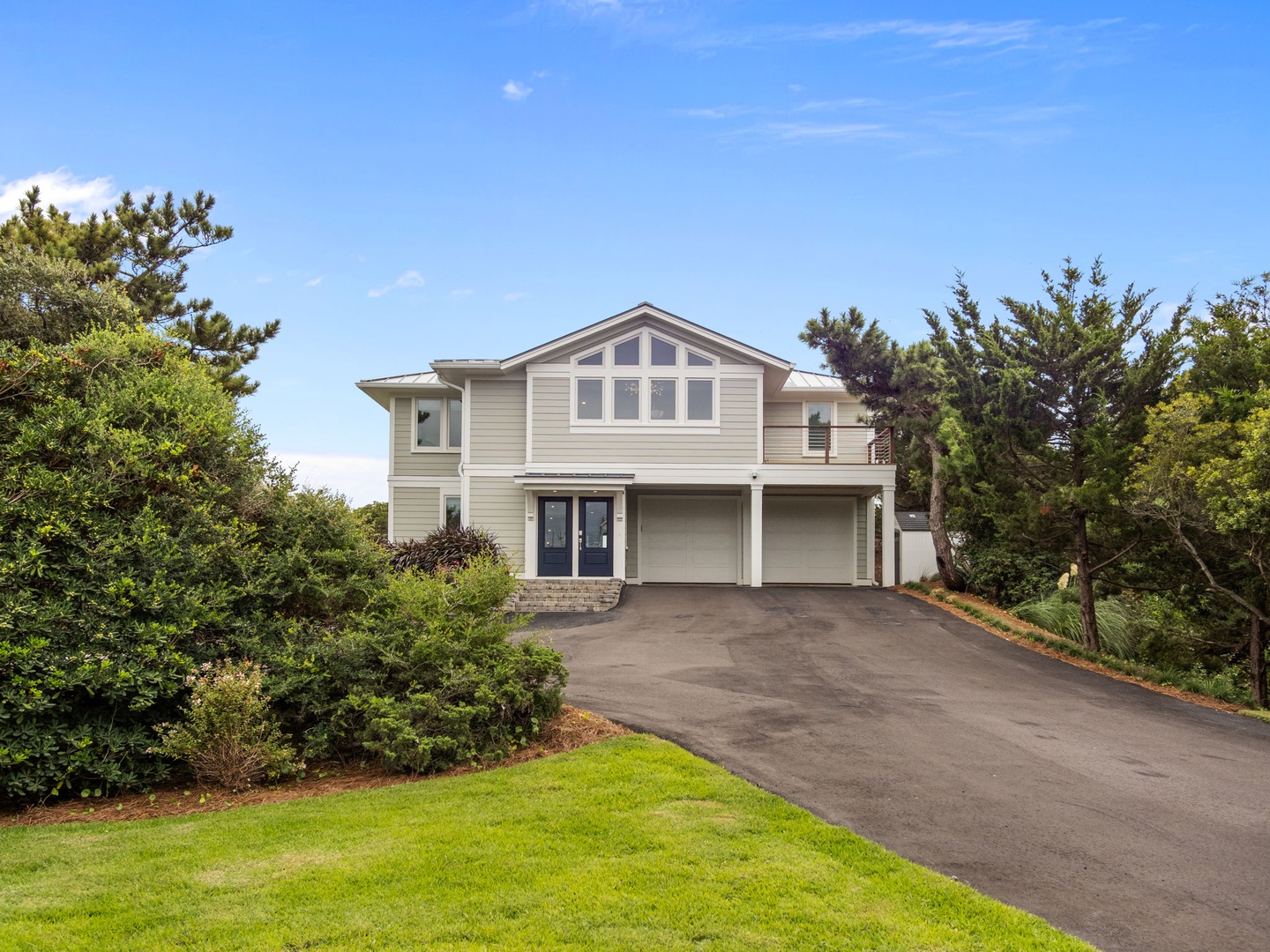 Modern two-story home with attached garage sits peacefully among mature trees and manicured landscaping.