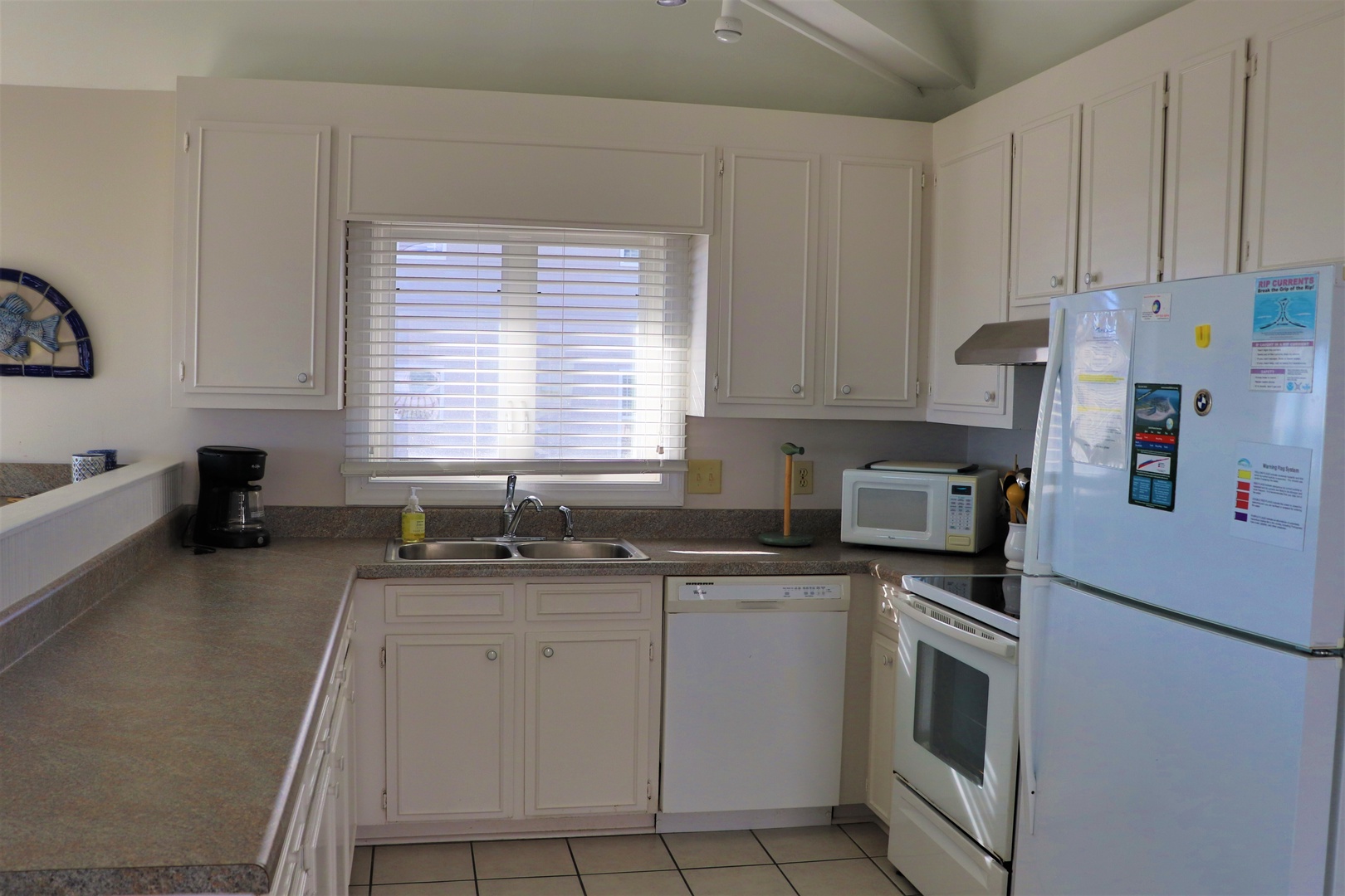 Your spacious kitchen features ample counter space for meal prep, complete appliances, and natural light streaming through blinds for comfortable cooking.
