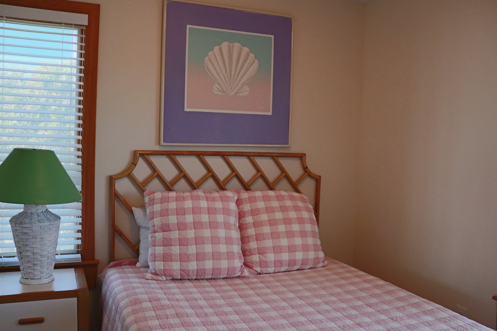 Drift off in comfort with soft pink gingham linens and cheerful coastal artwork adorning your peaceful bedroom retreat.