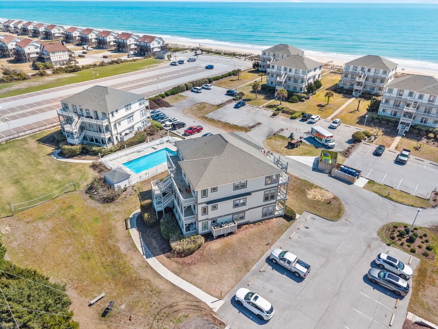 Oceanfront vacation rental community with swimming pool and private beach access, situated among coastal homes with stunning sea views.