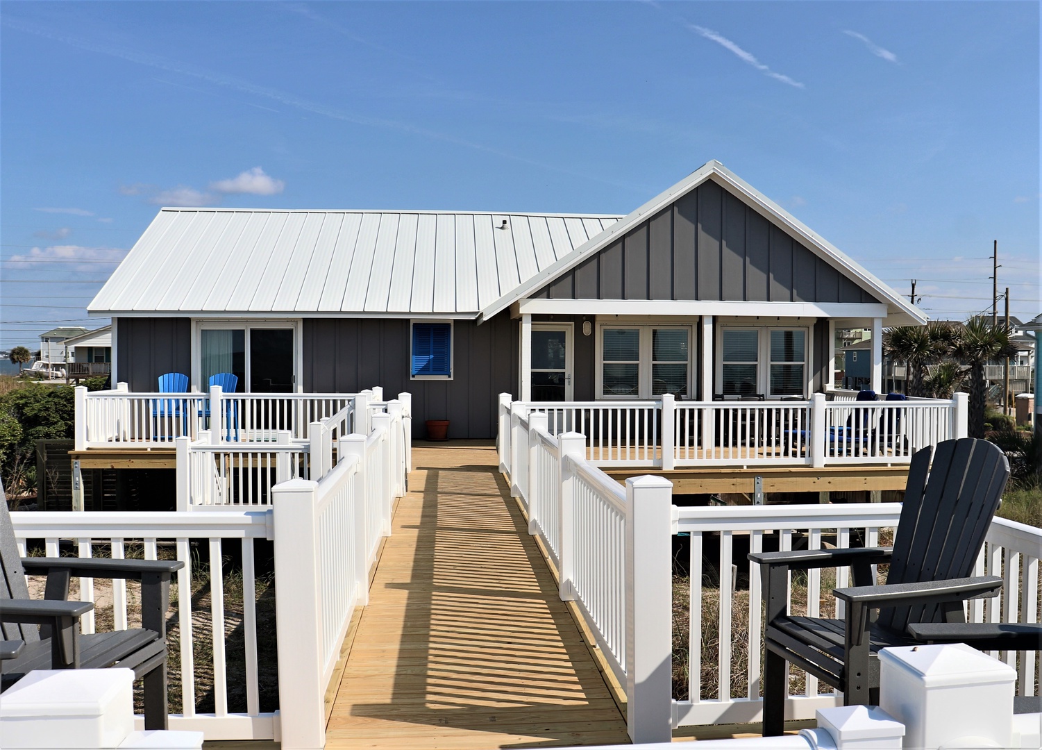 A charming coastal home with wraparound deck and blue accents captures the essence of beachside living.