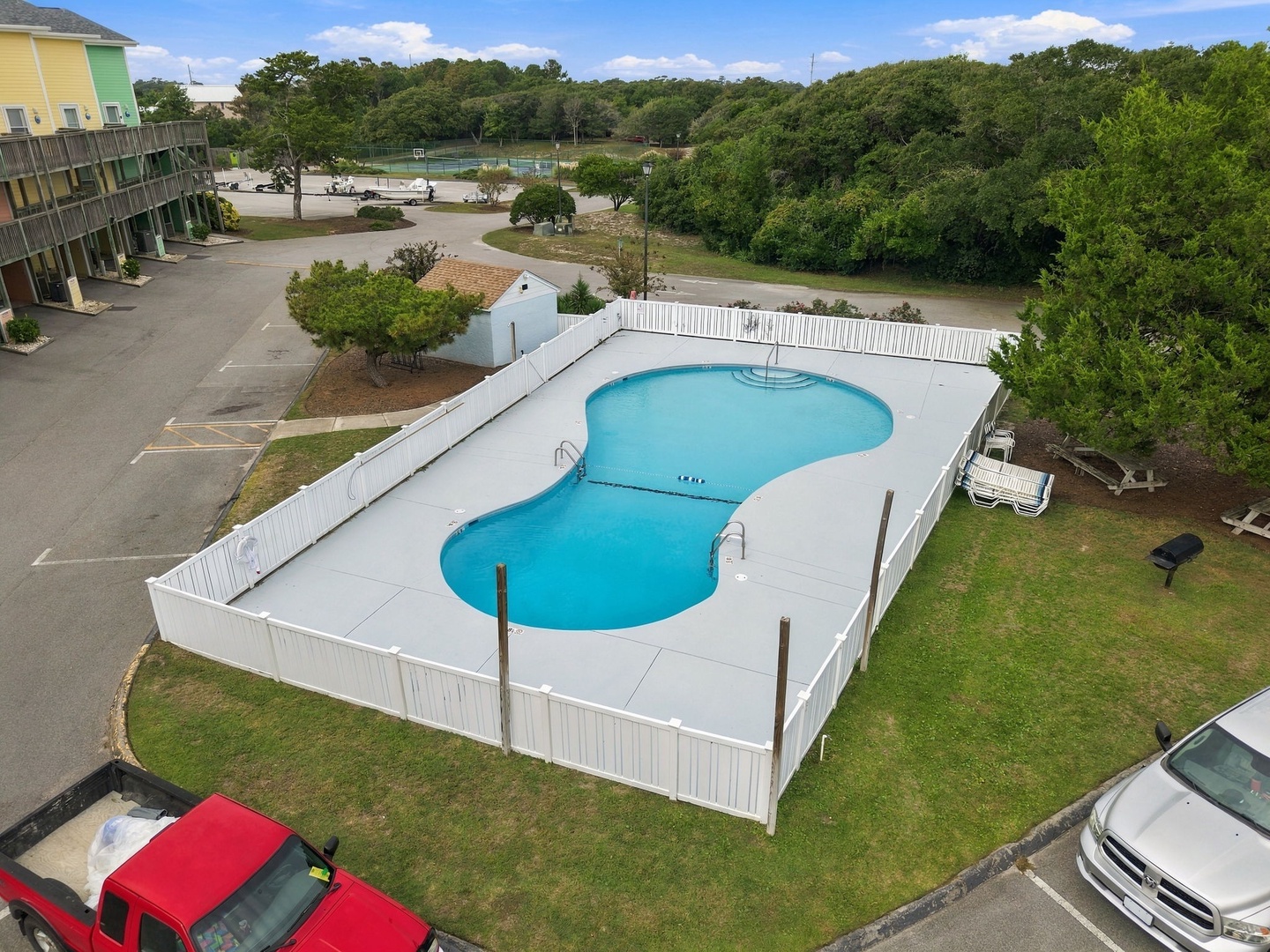 The property features a uniquely shaped pool surrounded by lush greenery and convenient parking, offering a peaceful setting for your coastal getaway.