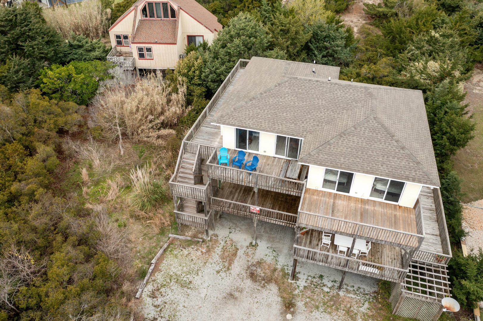 Aerial view of the property showing multi-level decks with outdoor seating areas surrounded by natural wooded landscape.