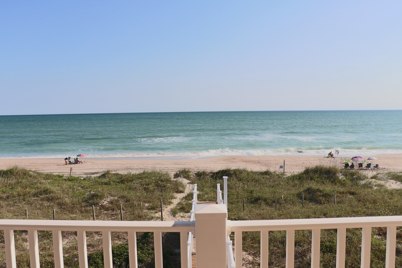 Pristine beachfront stretches along turquoise waters, with natural dune vegetation creating a peaceful coastal setting.