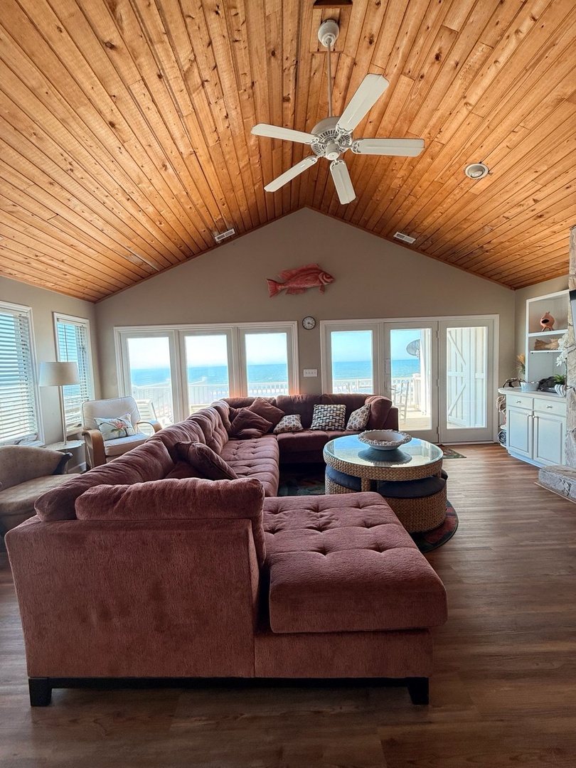 Sink into the plush sectional and gaze out at stunning ocean views framed by floor-to-ceiling windows. The vaulted wood ceiling and coastal charm create your perfect retreat.
