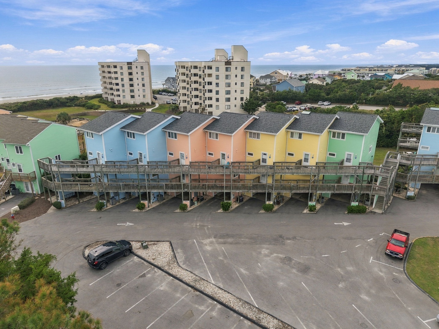 This coastal property features a row of colorful vacation rentals with nearby beach access, abundant parking, and ocean proximity in a scenic beachside community.