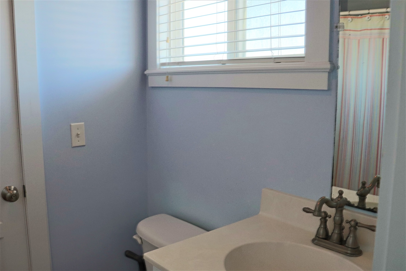 Refresh in your private powder room with classic fixtures and natural light streaming through the window.