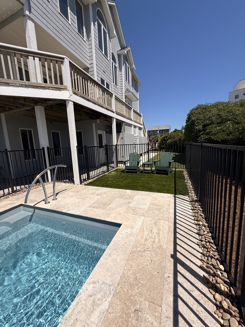 Modern poolside retreat featuring a sparkling swimming pool with natural stone decking, a shaded pergola for relaxation, and well-manicured lawns perfect for enjoying sunny days.