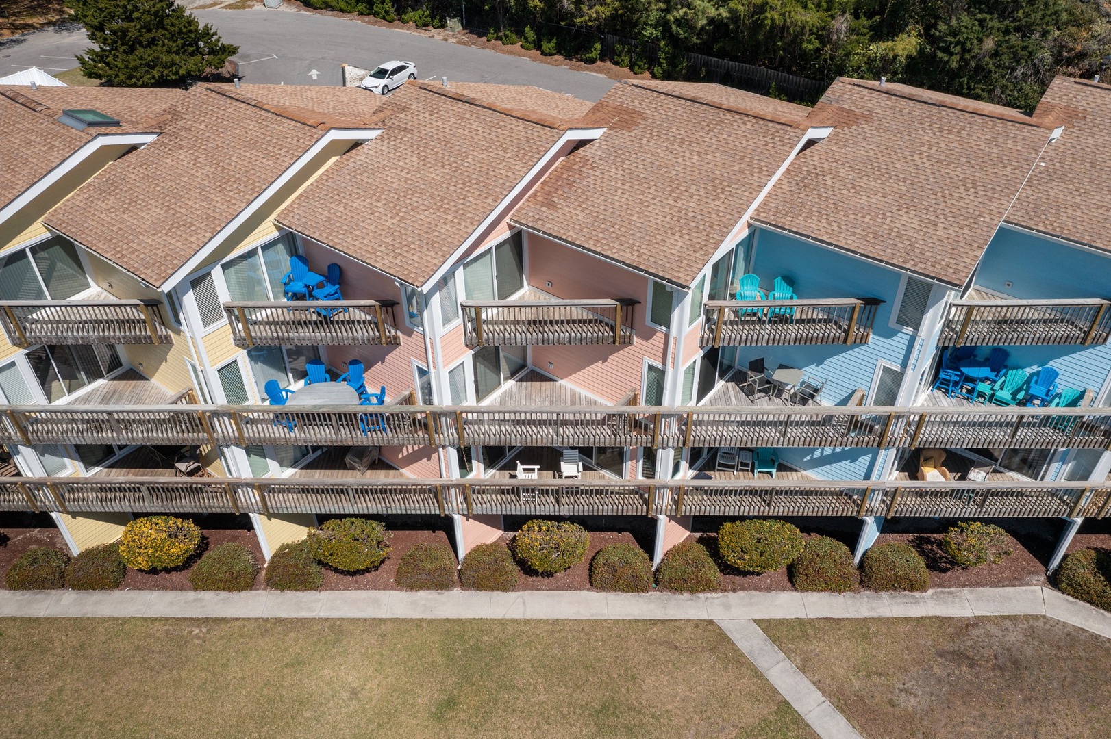 Aerial view of colorful beachfront vacation rental units with private balconies and outdoor seating areas.