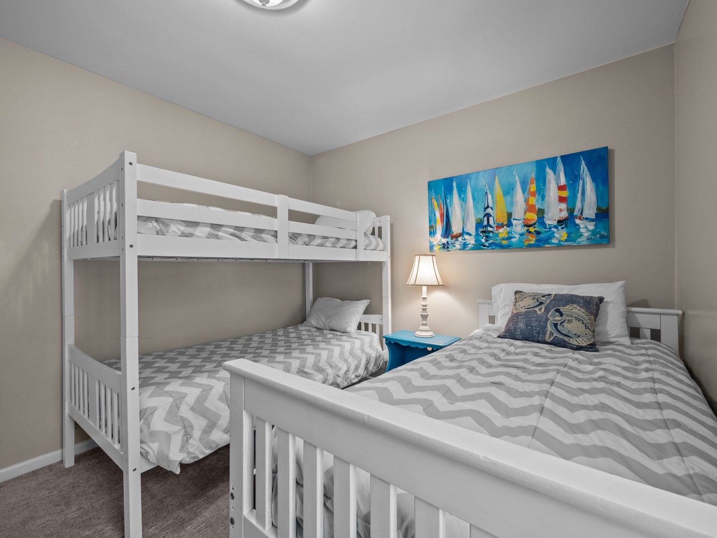Your cozy bedroom features comfortable beds with cheerful sailboat art, perfect for families with children seeking a restful coastal retreat.