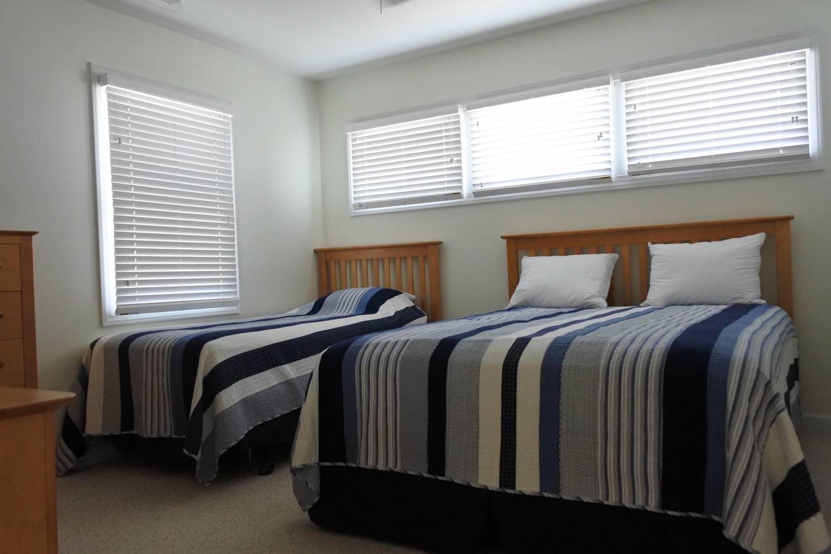 Rest peacefully in this bright twin bedroom, where matching striped linens and warm wood headboards create your comfortable retreat.