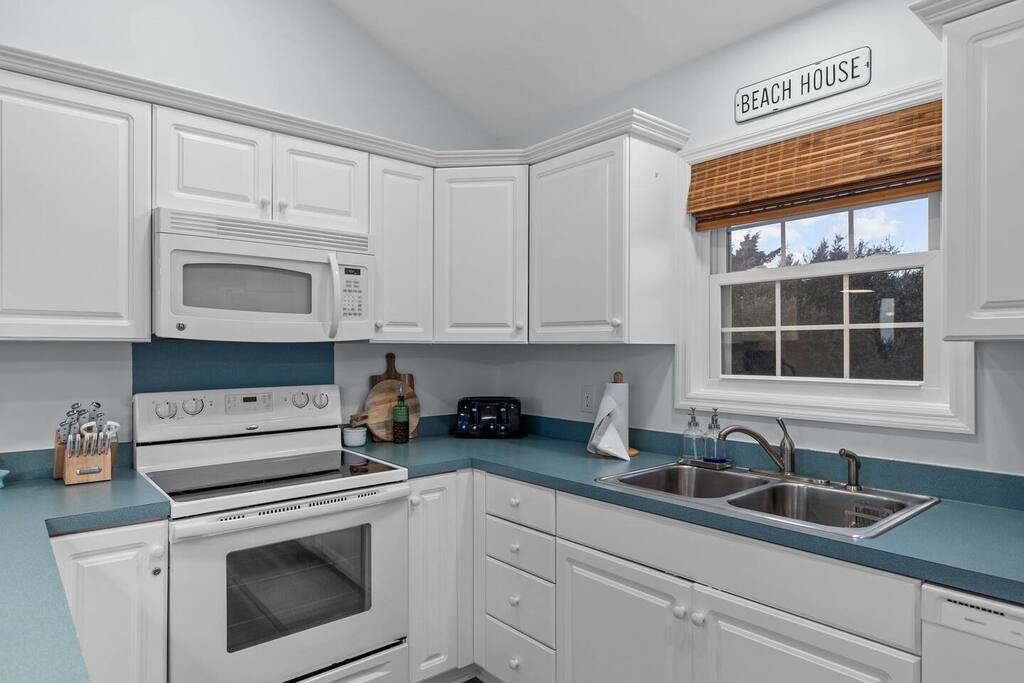 Your coastal-inspired kitchen awaits with crisp white cabinets, ocean-blue countertops, and everything you need to create delicious meals during your stay.