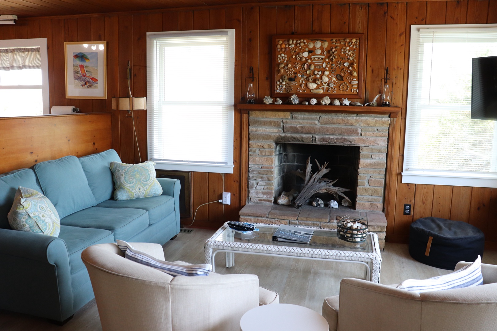 Cozy up in your charming living room featuring warm wood paneling, a stone fireplace, and comfortable seating for relaxing evenings.