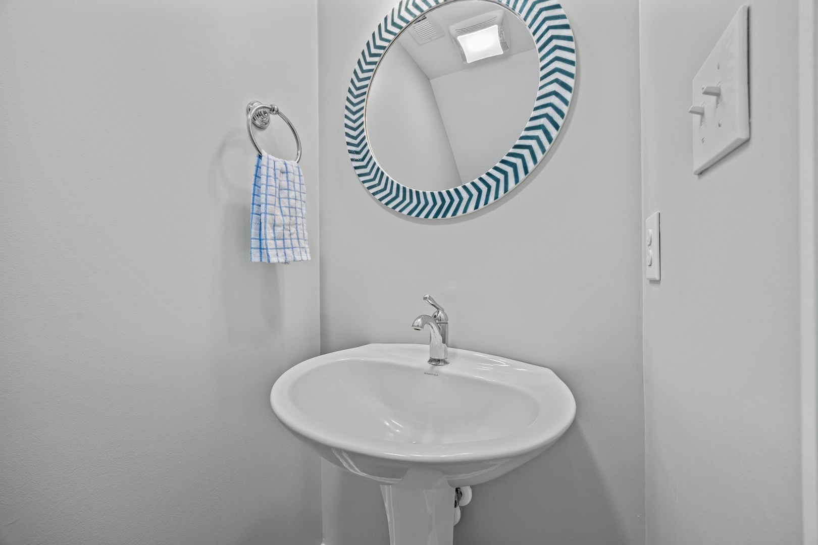 Refresh in your bright, clean powder room with modern fixtures and thoughtful touches like the colorful striped mirror.