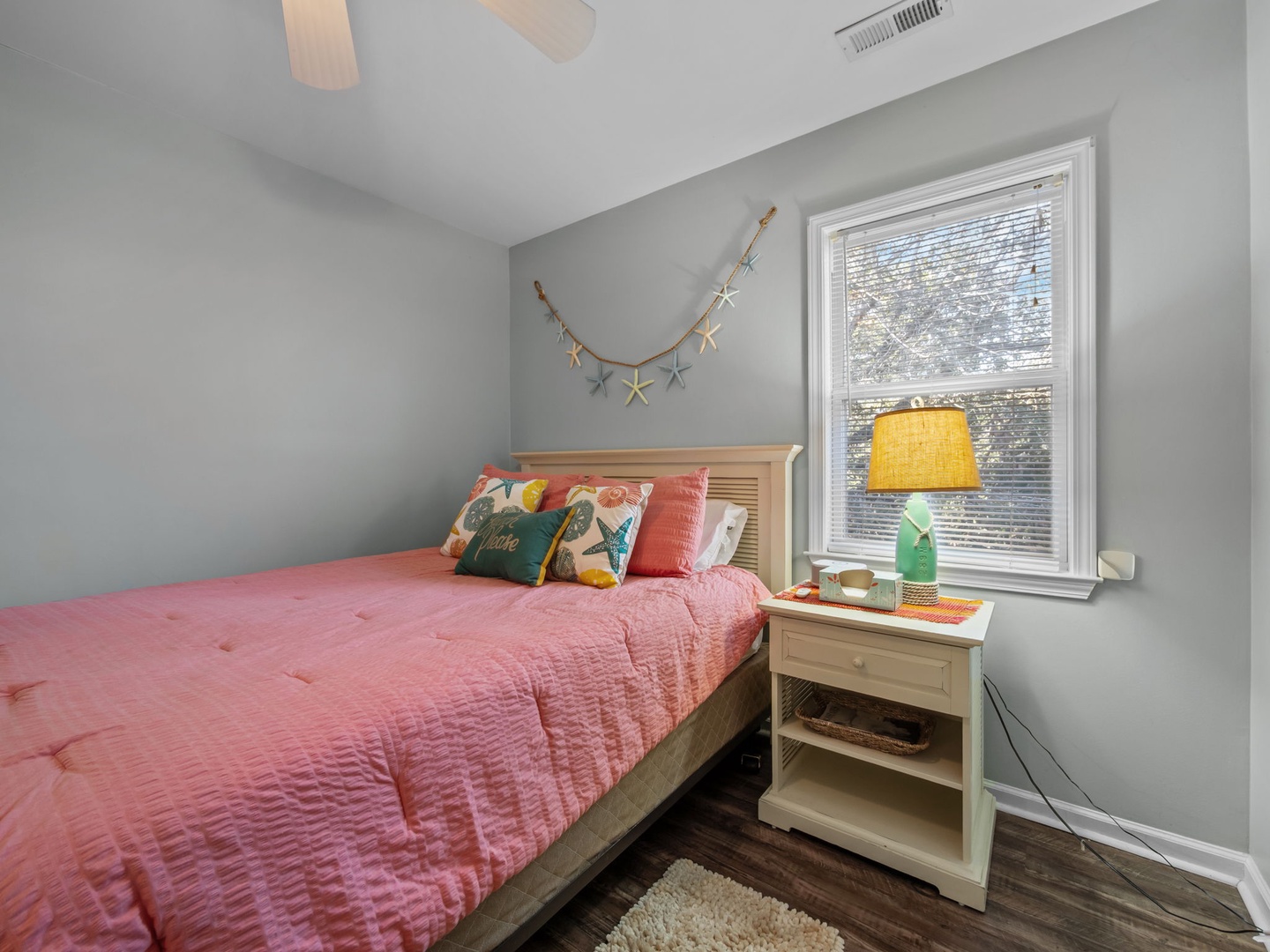 Drift off to dreamland in your cozy bedroom, where coral bedding and whimsical starfish décor create a beachy retreat.