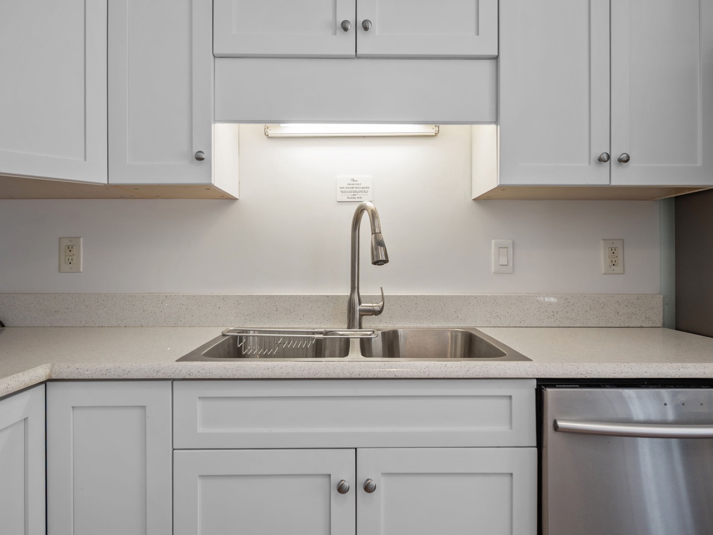 You'll love preparing meals in this pristine kitchen featuring elegant gray cabinetry, gleaming countertops, and modern stainless steel appliances.