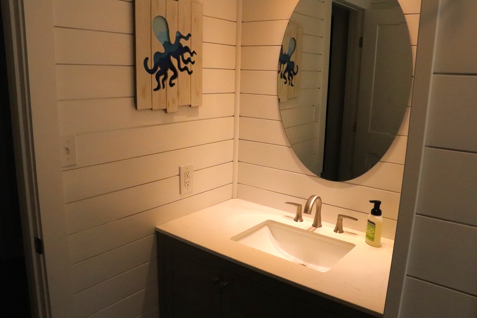 Your modern bathroom features sleek vanity with round mirror and charming nautical touches that create a welcoming coastal retreat.