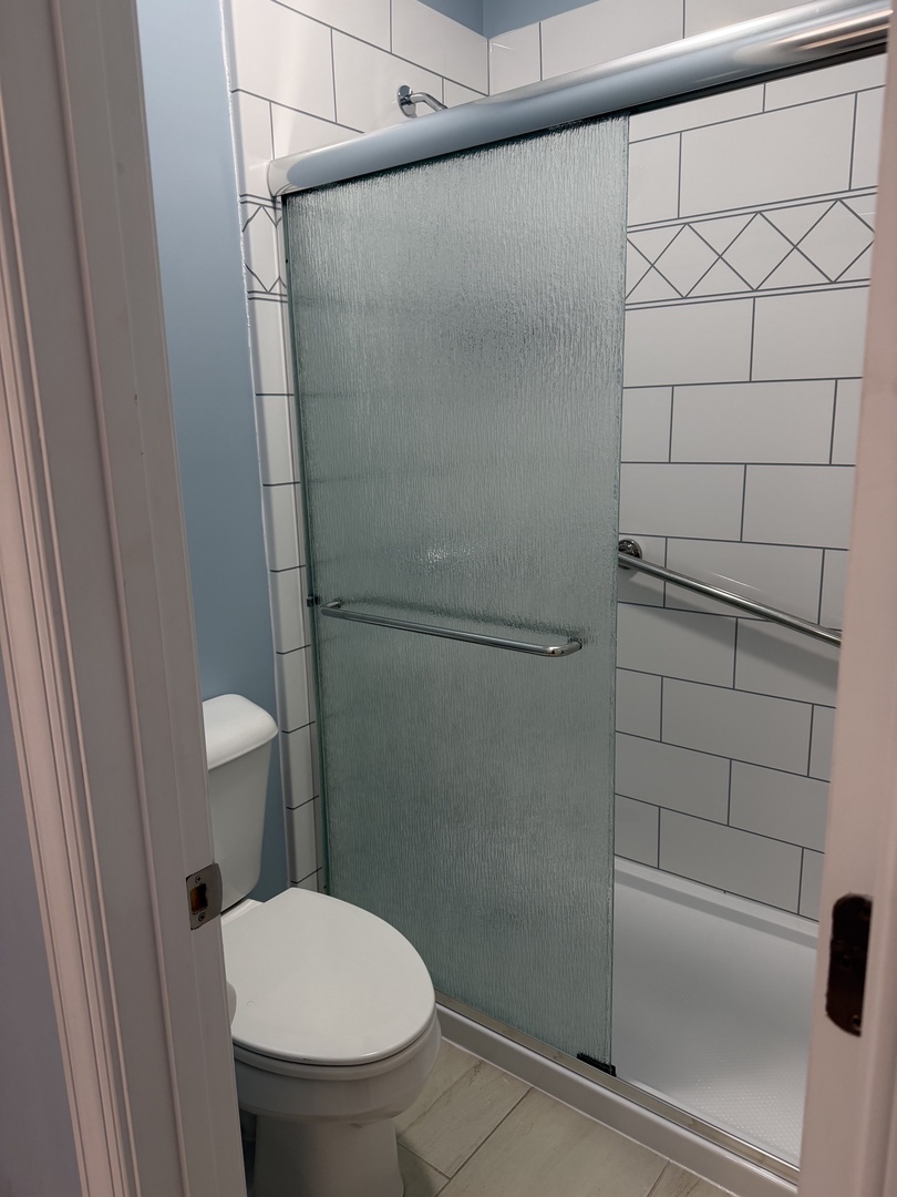 Your private bathroom features a sleek walk-in shower with frosted glass, fresh white tiles, and modern fixtures—perfect for unwinding after your day of exploring.