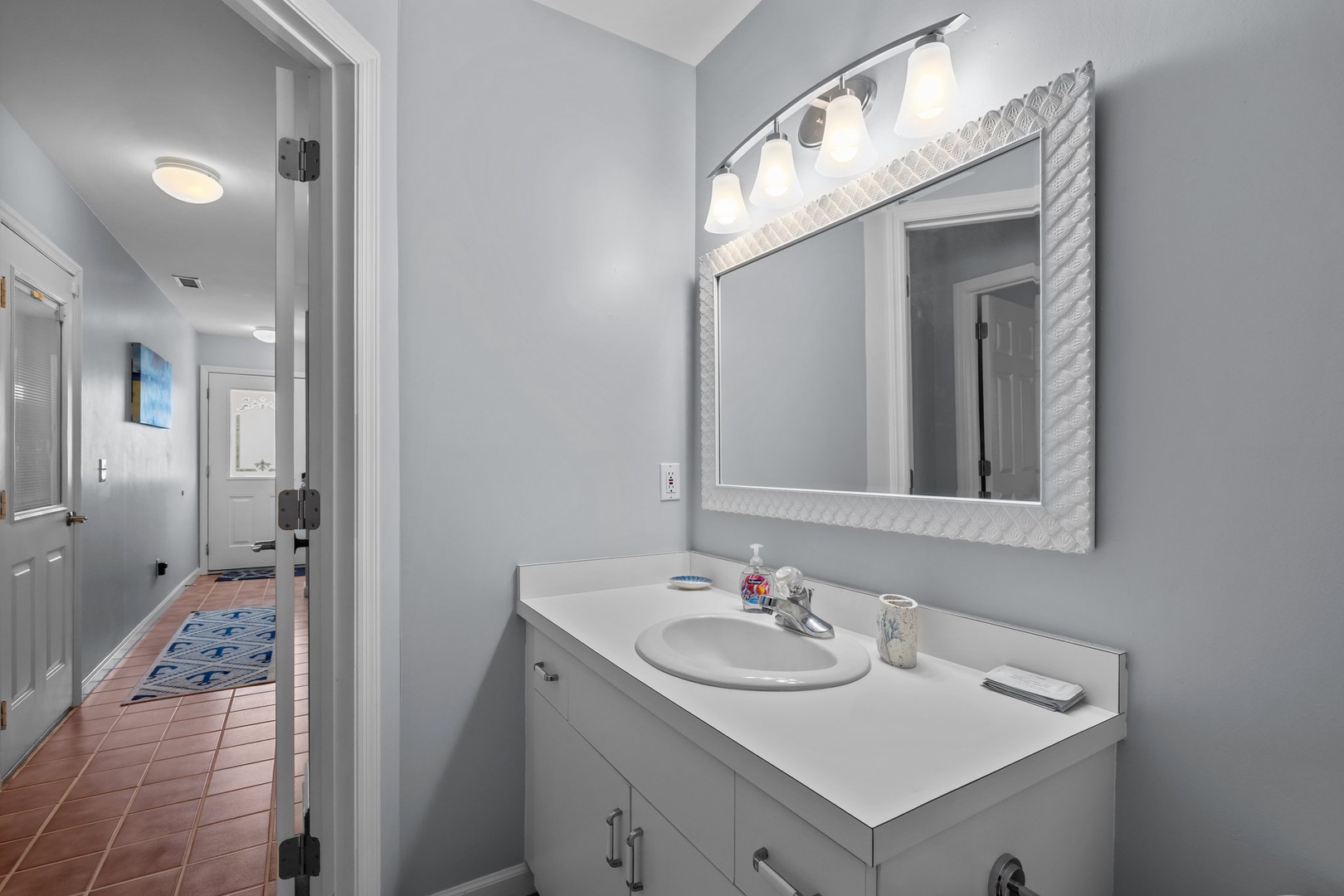 Your private bathroom features a spacious vanity with ample counter space and a beautiful textured mirror frame to start your day refreshed.