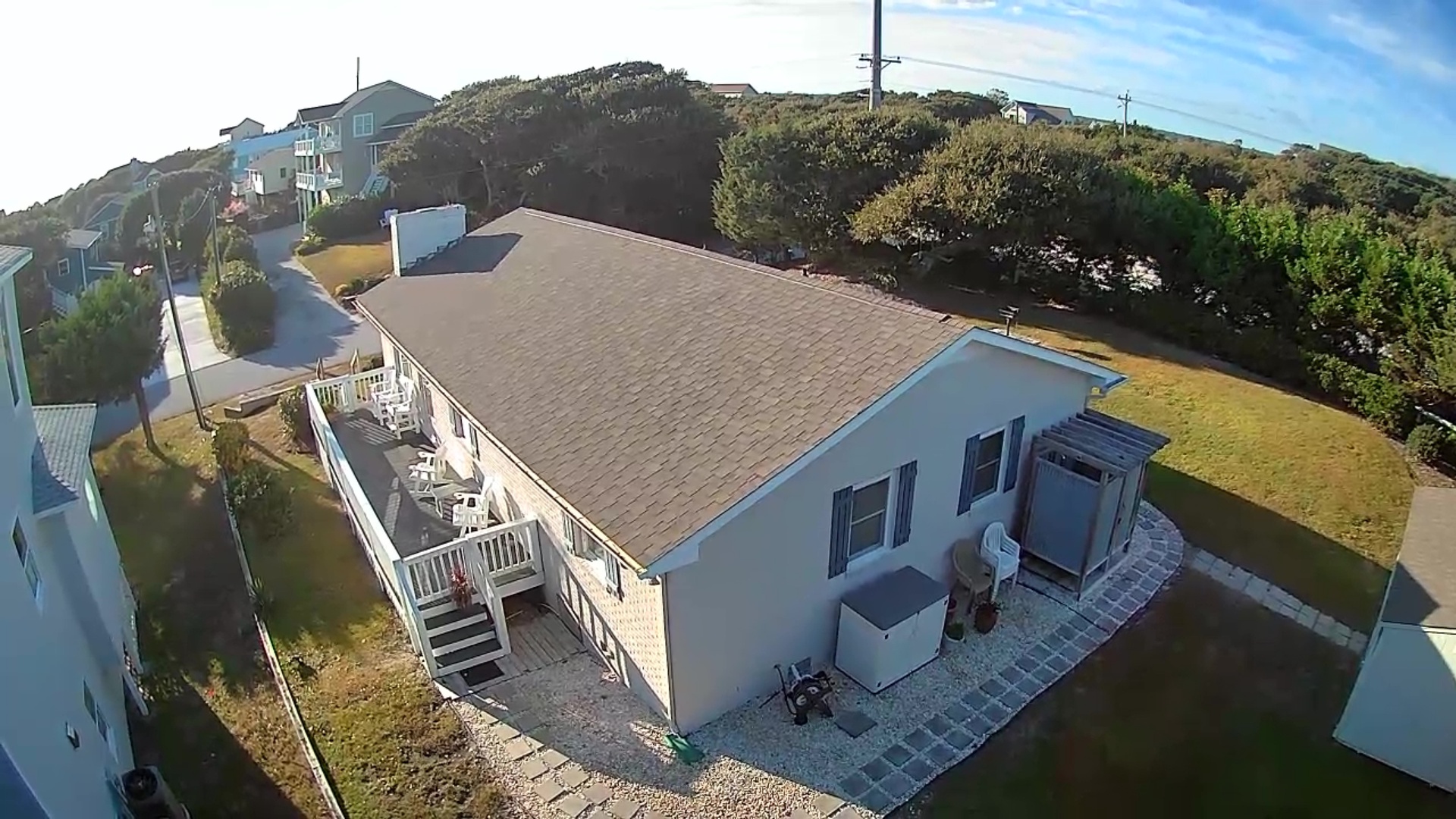 Elevated aerial view of coastal rental property with spacious deck and hillside setting near ocean.