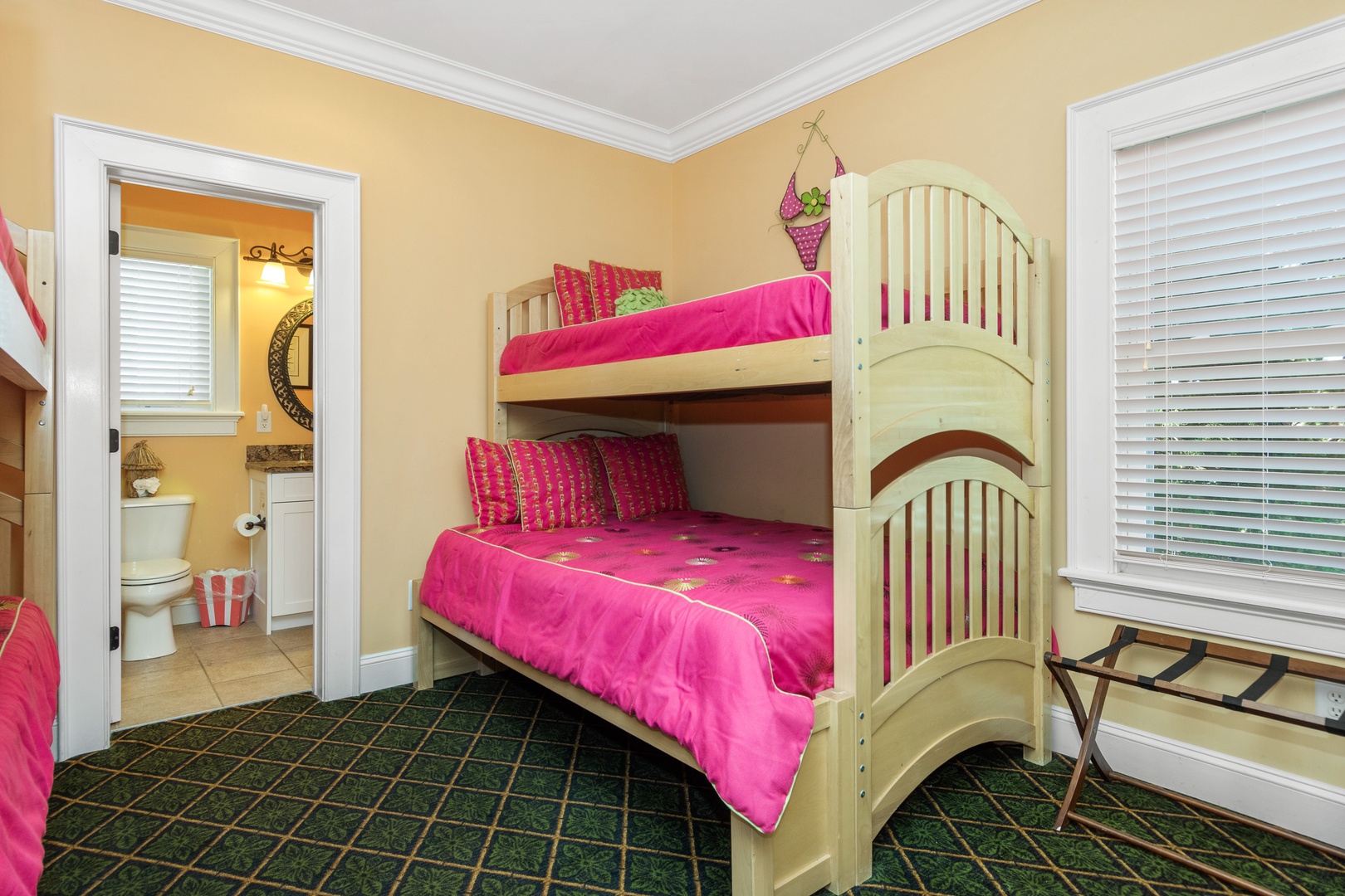 Your little ones will love this cheerful bunk bed room with vibrant pink bedding and an adjoining bathroom for convenience.