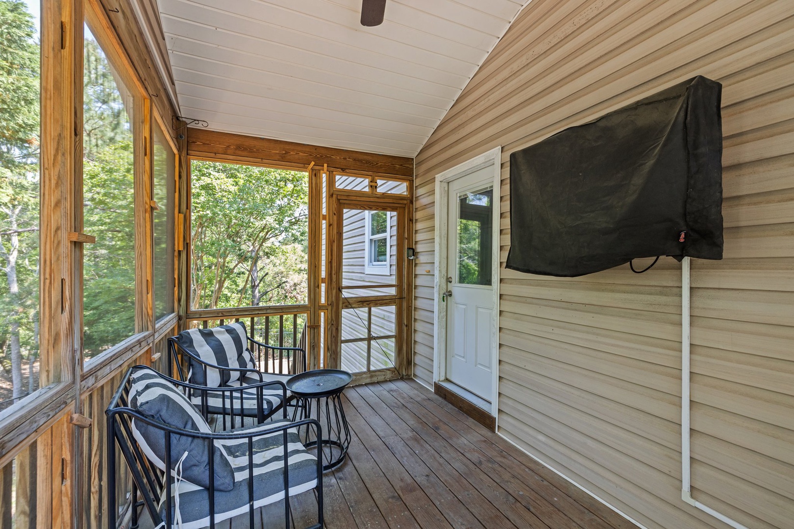Relax on your private screened porch with comfortable seating and outdoor TV, surrounded by peaceful tree views for perfect morning coffee or evening unwind moments.