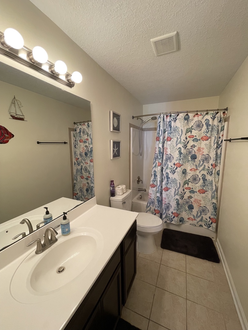 Unwind in your private bathroom featuring a luxurious soaking tub and charming coastal-themed blinds that create a serene, spa-like retreat.