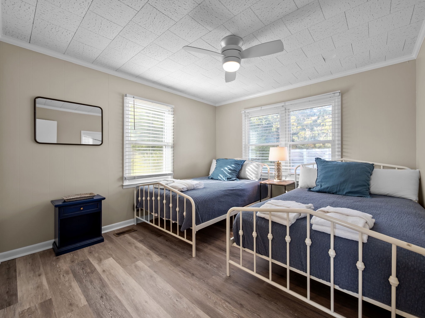 Drift off to sleep in your peaceful twin bedroom, where navy blue linens and gentle ceiling fan create a relaxing haven.