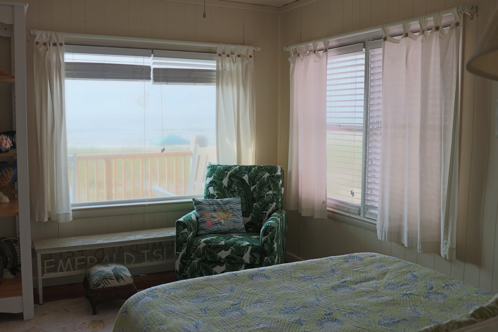 Curl up in your cozy reading chair by bright corner windows, where soft curtains filter natural light into your peaceful bedroom retreat.