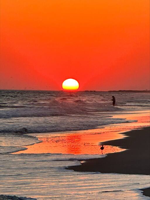 Stunning sunset paints the sky in brilliant orange hues over the nearby beach, creating a breathtaking backdrop for the area.