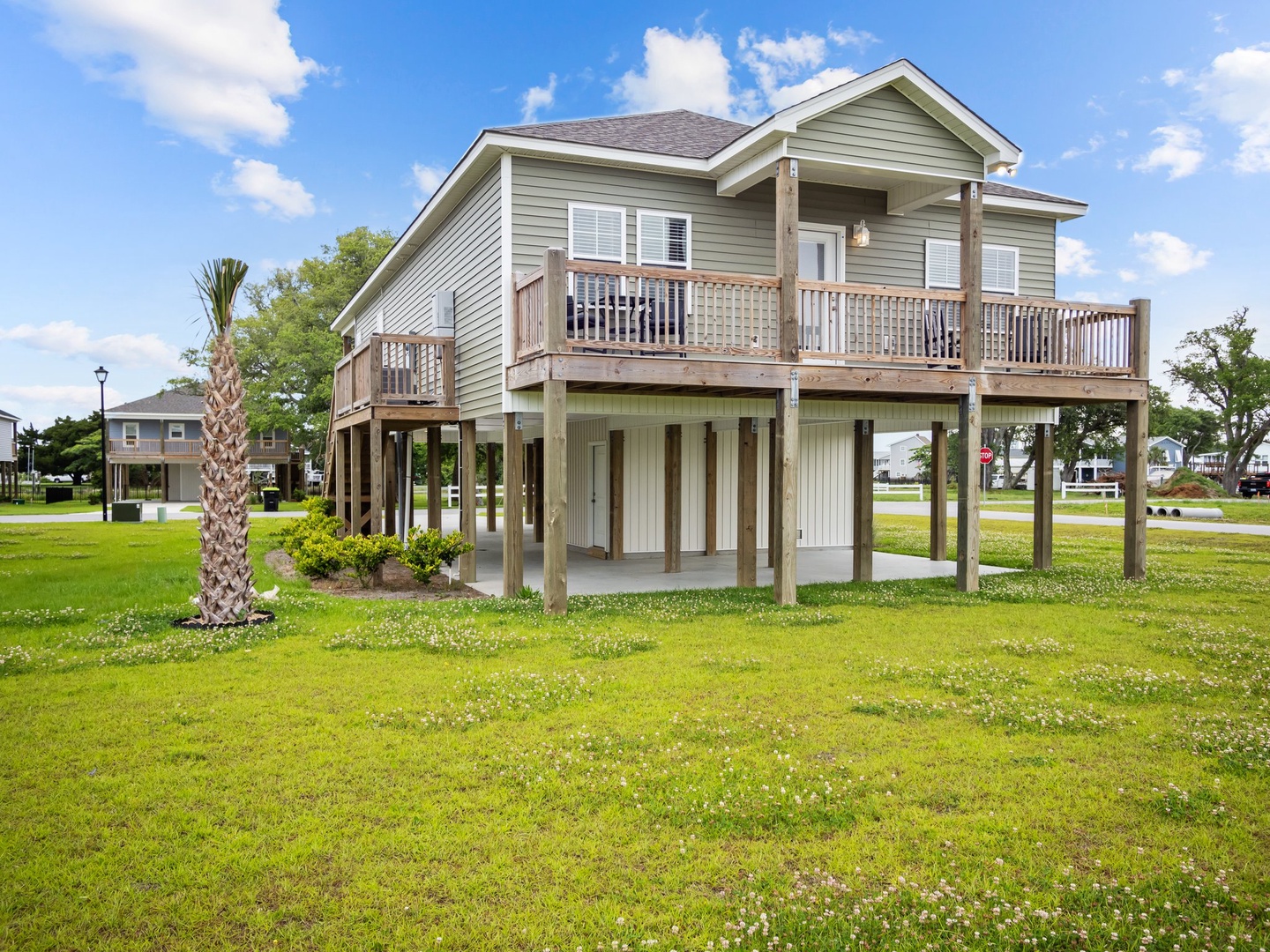 Charming coastal rental with spacious balcony and covered parking, surrounded by lush green grounds and tropical palms.