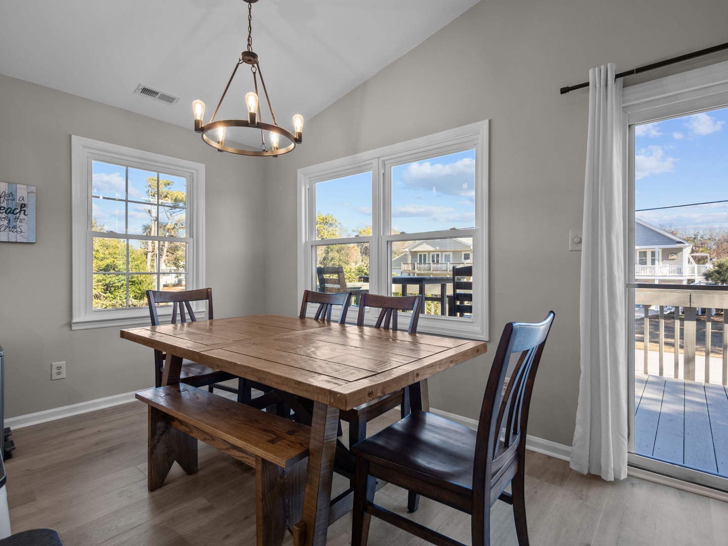 Your bright dining space features rustic charm with a stunning chandelier and sunny views through multiple windows.